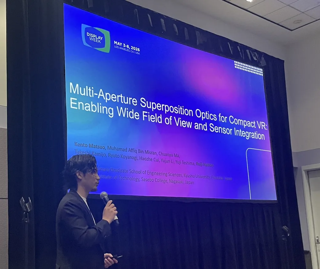 Kento Matsuo giving the oral presentation in the symposium hall at SID Display Week 2026, with the paper title on the screen behind him.